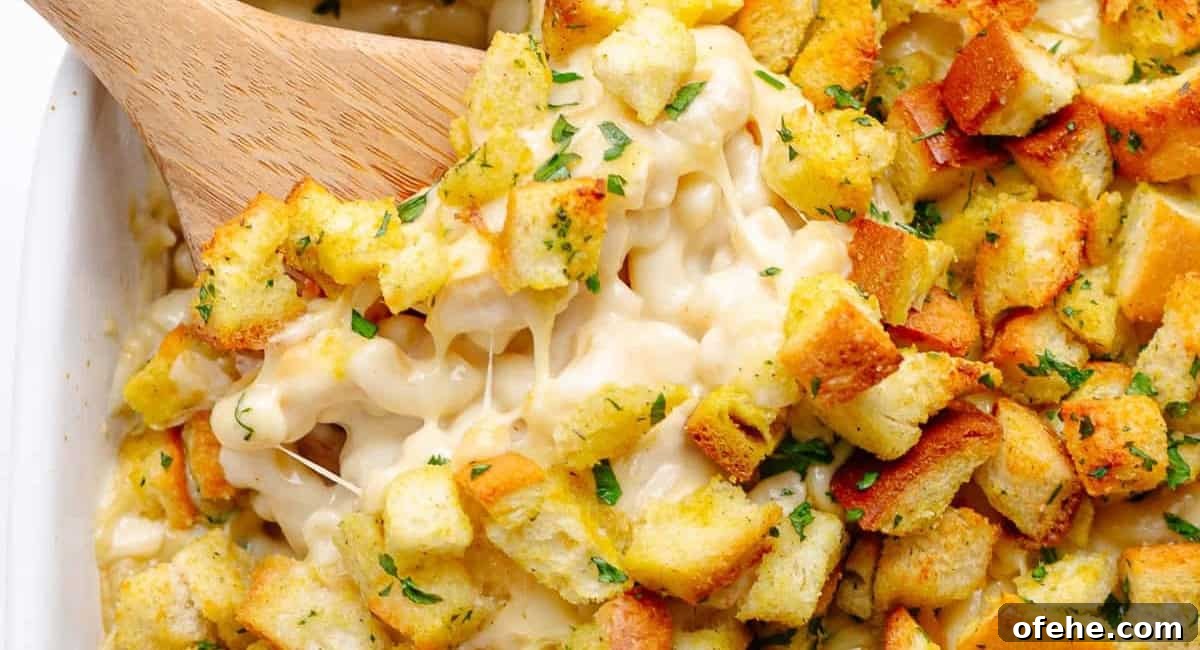 Overhead image of gouda mac and cheese with garnish and a wooden spoon.