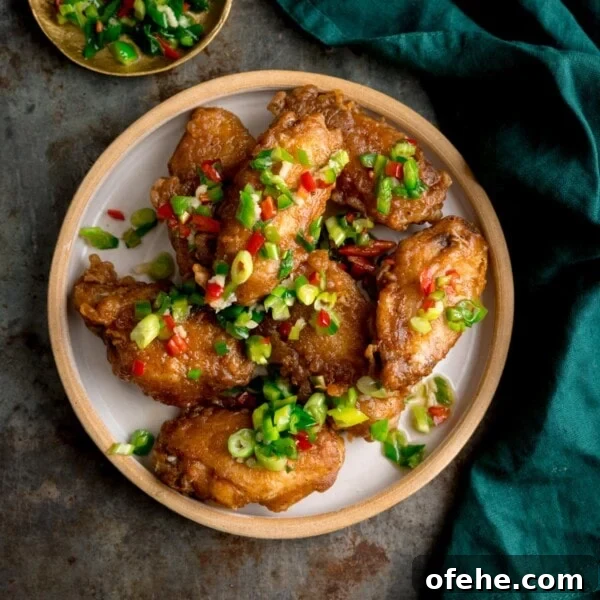 Crispy Chicken Lollipops Recipe: Finger-Licking Party Snack 13 Square overhead image of crispy salt and pepper chicken wings on a white plate on a rustic metal surface.