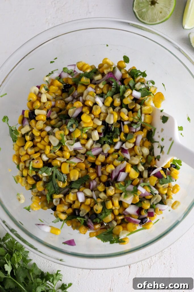 Vegan Elote-Style Corn Salad Recipe for Summer BBQs 7 cooked corn, red onion, and cilantro mixed in bowl