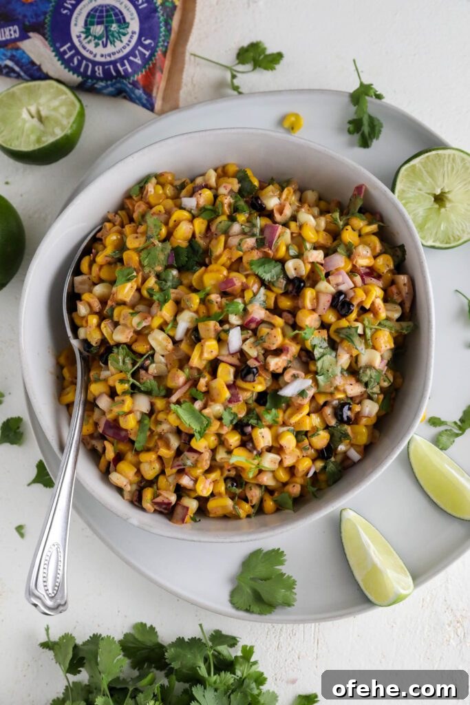 Vegan Elote-Style Corn Salad Recipe for Summer BBQs 9 Vegan Elote Corn Salad served in bowl with spoon on plate with lime slices