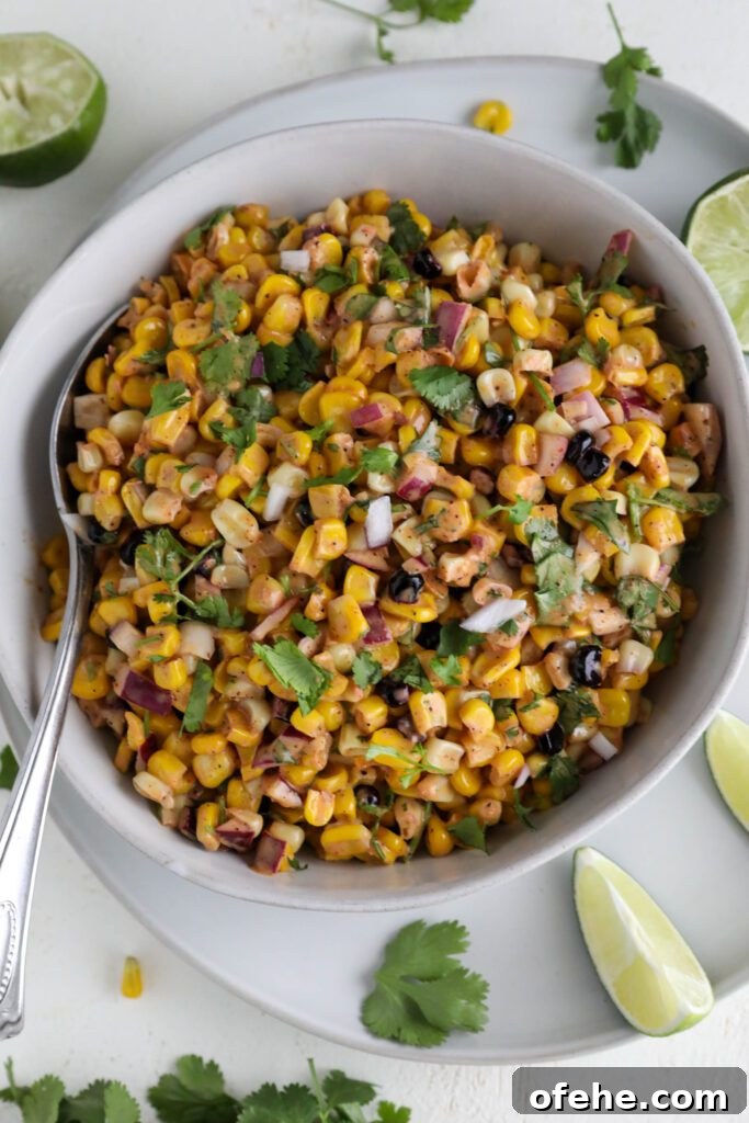 Vegan Elote-Style Corn Salad Recipe for Summer BBQs 10 Vegan Elote Corn Salad served in bowl with spoon on plate with lime slices