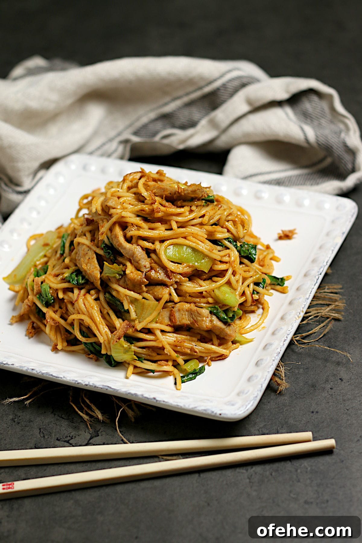 Sichuan-Style Spicy Pork Noodles with Bok Choy 3 Spicy Noodles with Pork and Bok Choy on a square, white plate.