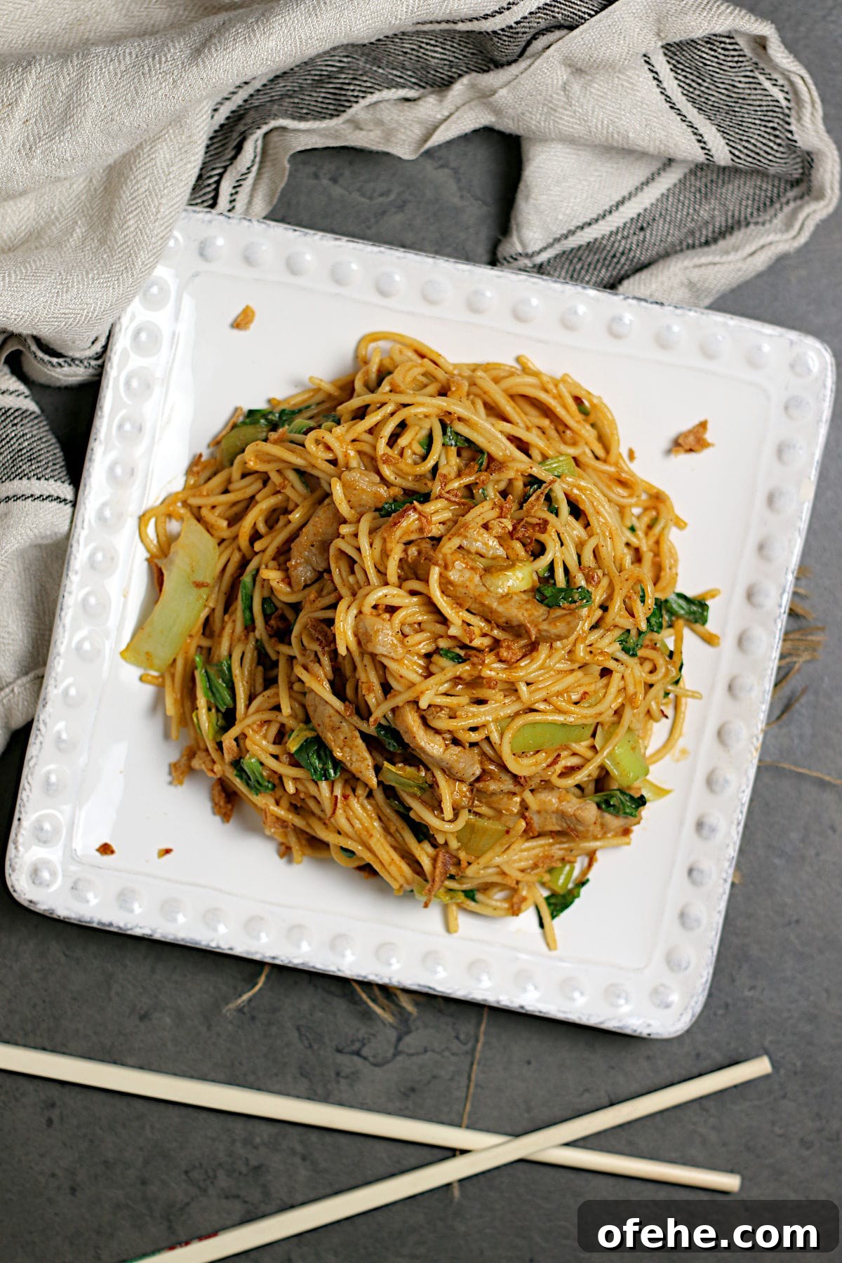 Sichuan-Style Spicy Pork Noodles with Bok Choy 4 An overhead photo of Spicy Noodles with Pork and Bok Choy on a square, white plate.