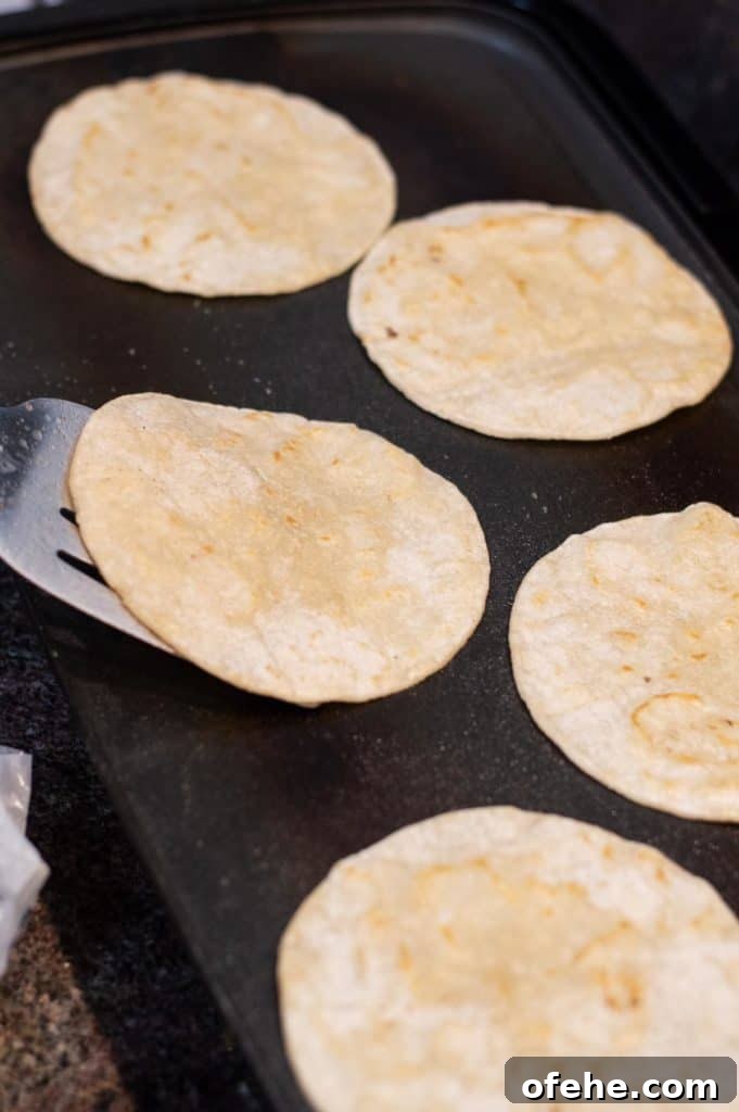 Classic Ground Beef Tacos: Grandma’s 60-Year Family Recipe 8 corn tortillas frying on the griddle