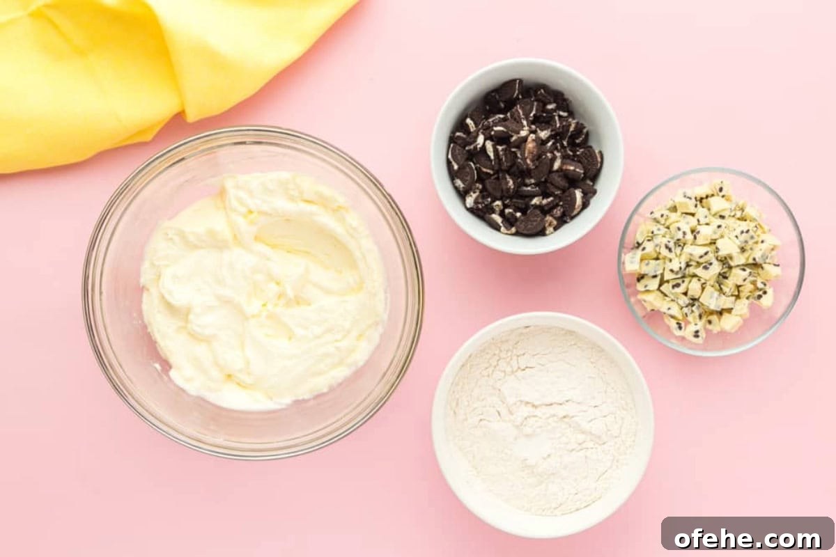 Edible Oreo Cookie Dough Recipe You Can Eat Raw 6 creamed butter and sugar in a glass bowl next to bowls of flour, chopped cookies, and chopped white chocolate candy bars.