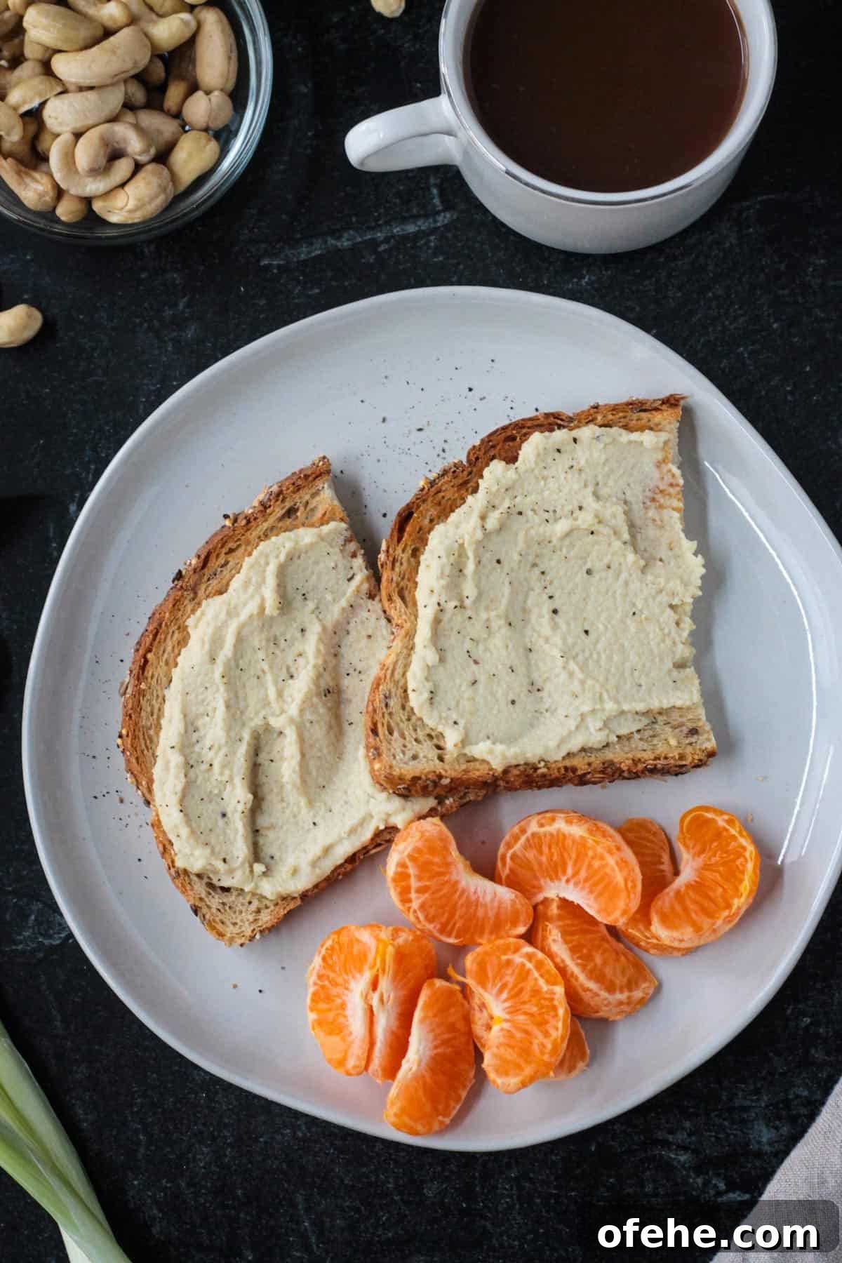 Creamy Vegan Cashew Ricotta Recipe for Pasta & Pizza 6 Vegan ricotta spread on two slices of toast next to a pile of orange segments.