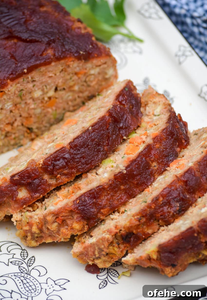 slices of cranberry sauce topped turkey meatloaf on a black and white serving platter