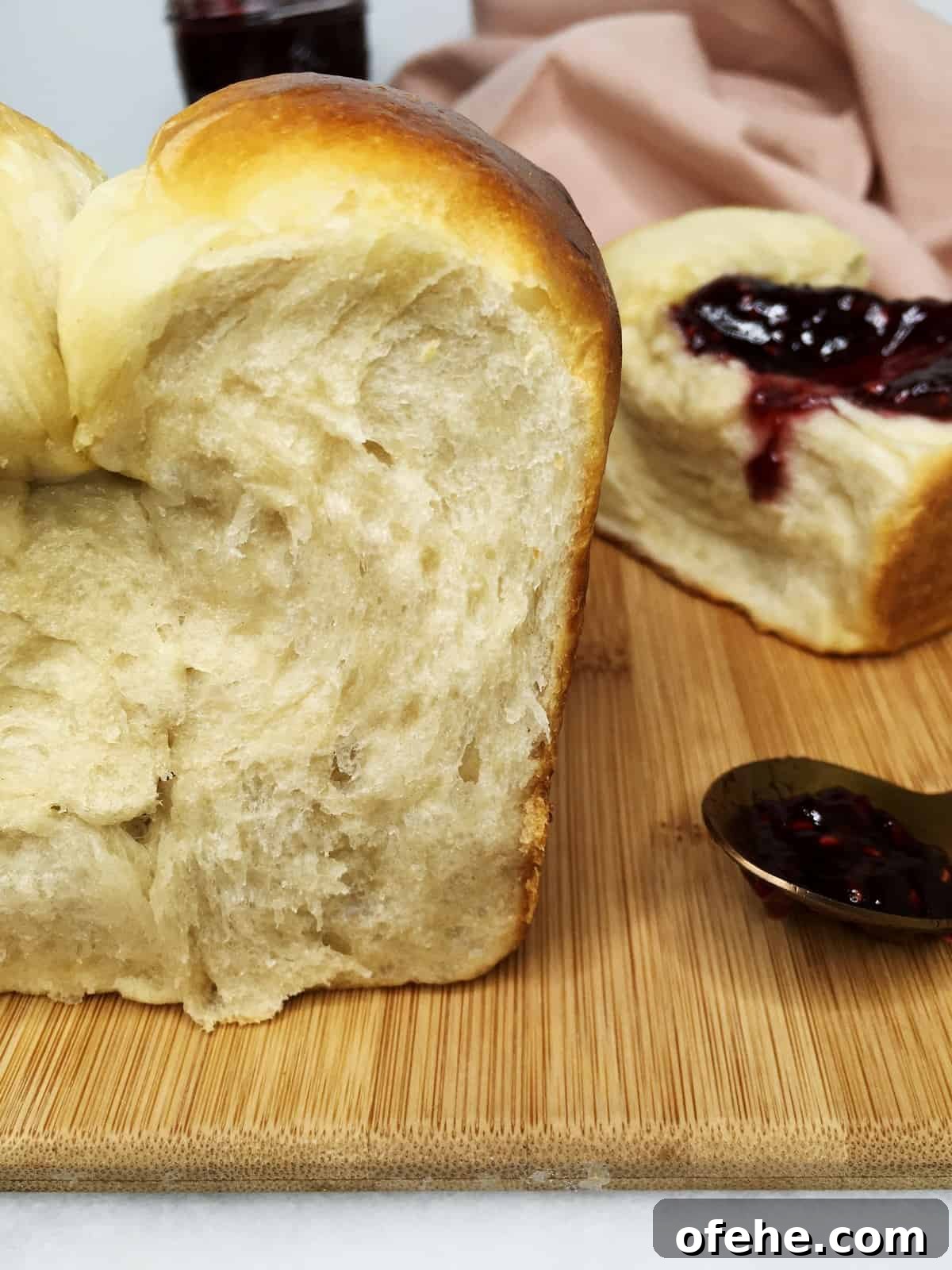 Authentic French Brioche Recipe for Soft, Buttery Loaves 4 Sliced quick brioche with a bun and a spoon full of jam on a wooden board