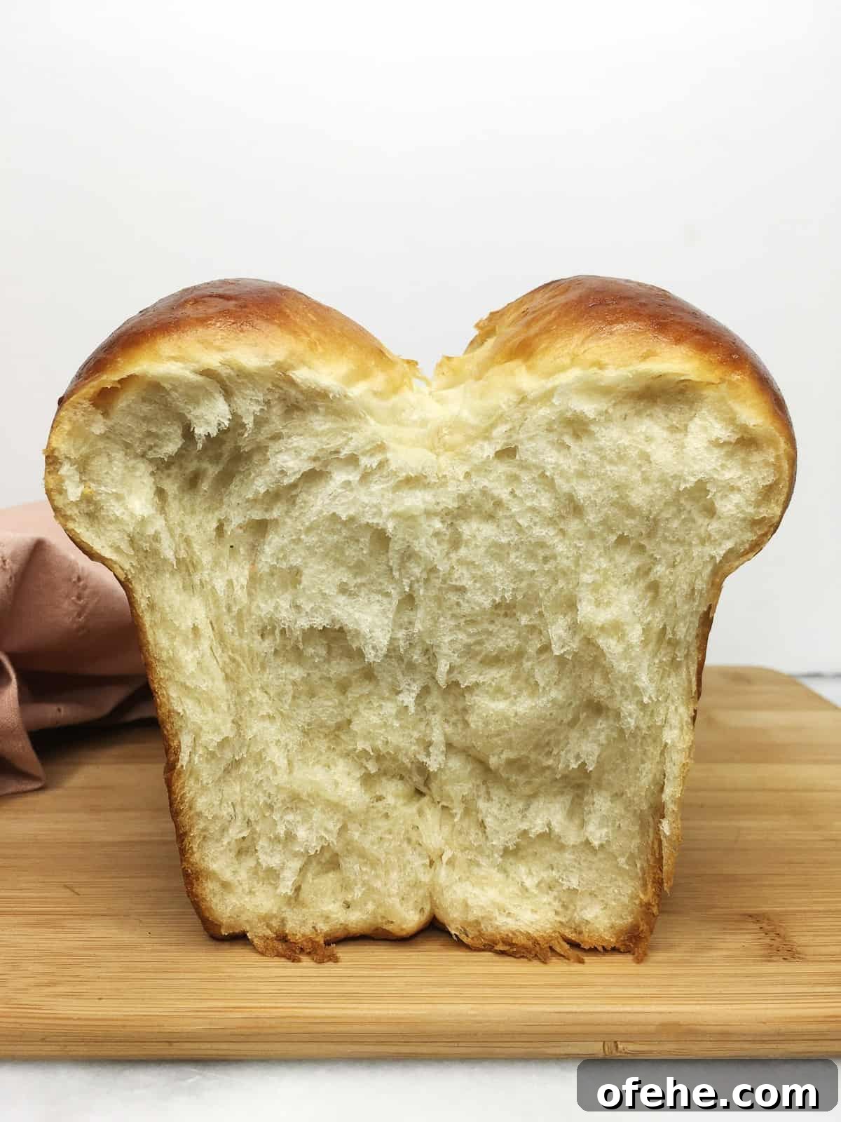 Authentic French Brioche Recipe for Soft, Buttery Loaves 5 Sliced brioche bread on a wooden board with a towel in the background