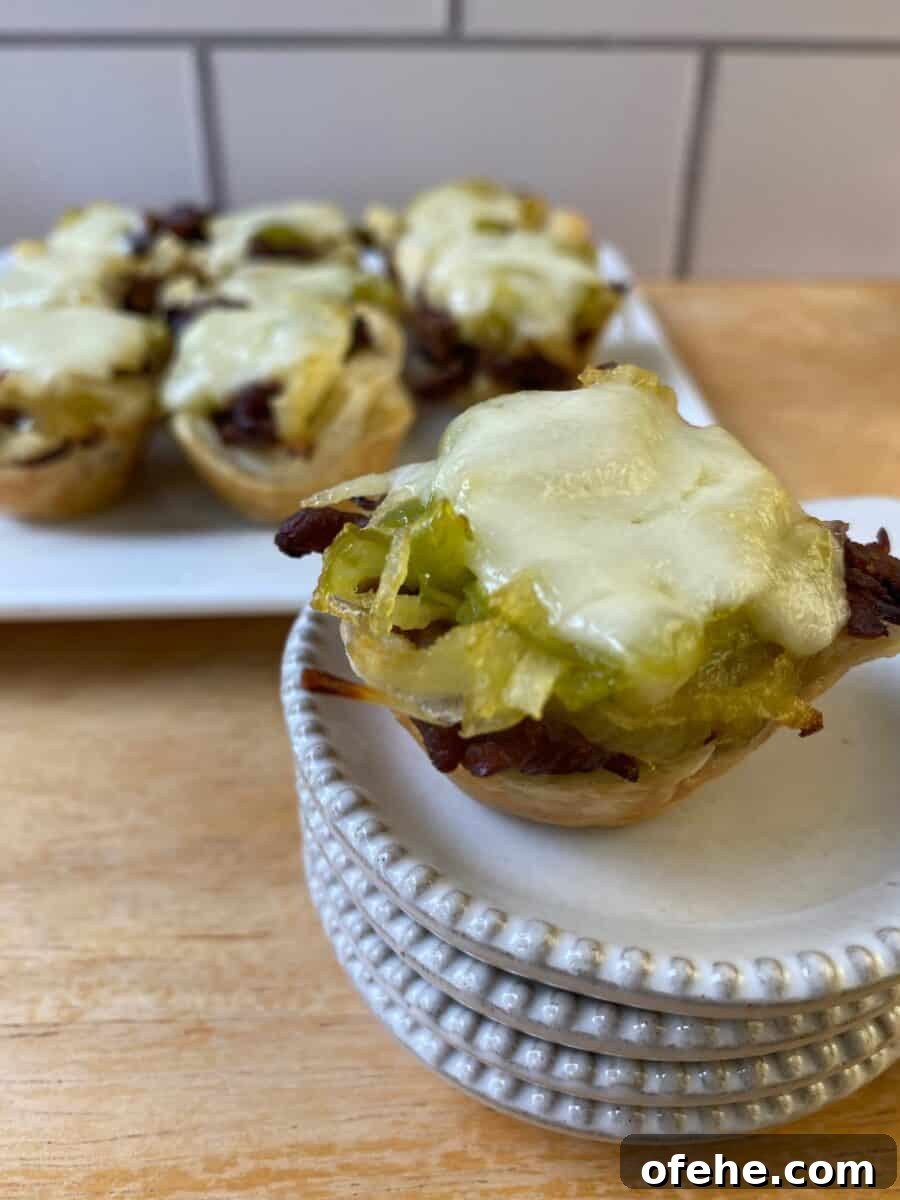 Philly Cheesesteak Bites Recipe: Savory Mini Sandwich Appetizers 2 Philly Cheesesteak bite on a small stack of dishes with the serving plate in the background.