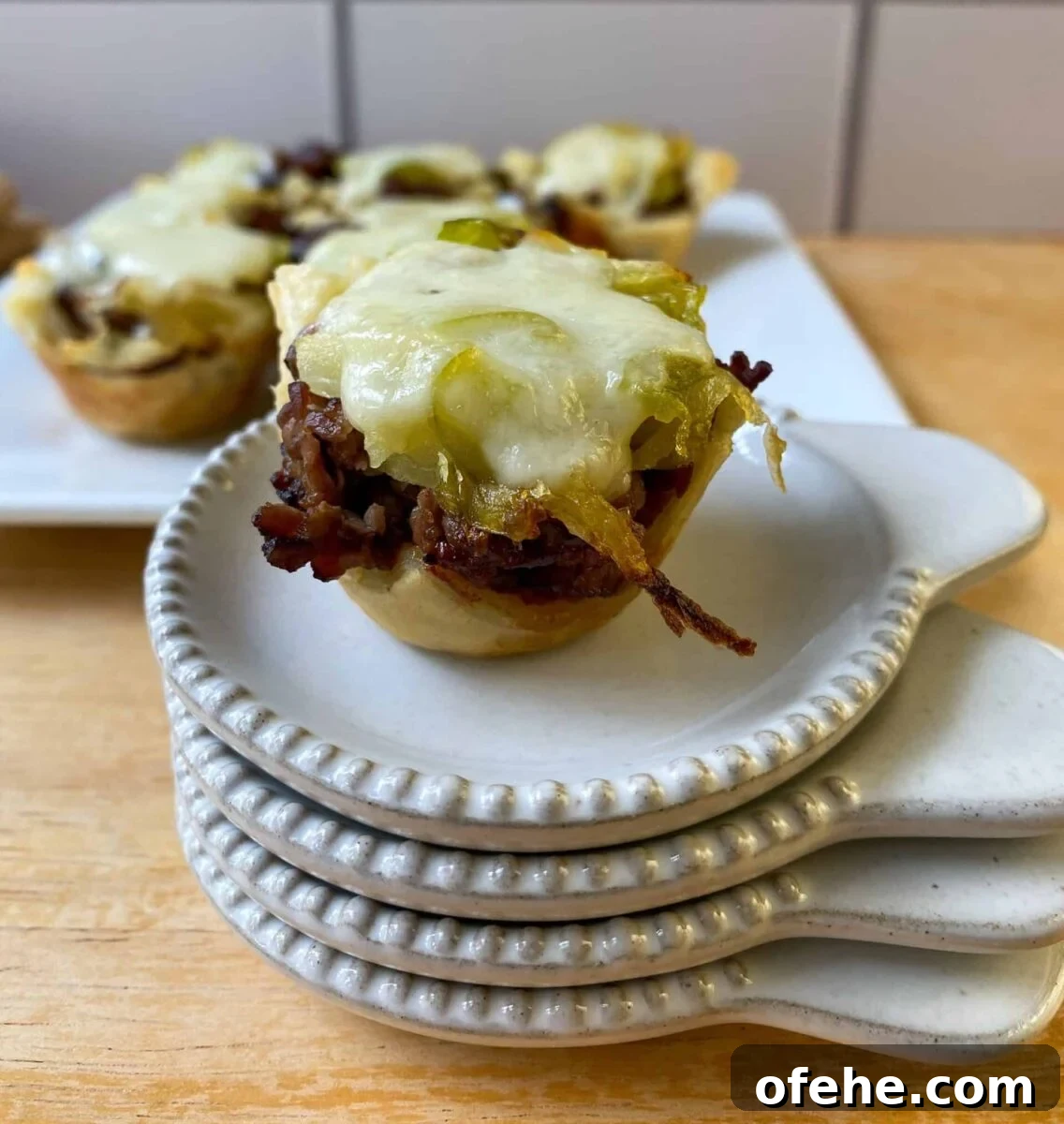 Philly Cheesesteak Bites Recipe: Savory Mini Sandwich Appetizers 10 mini cheesesteak bite on a stack of tasting plates.