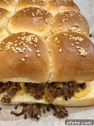 A pan of baked cheeseburger sliders on a baking sheet.