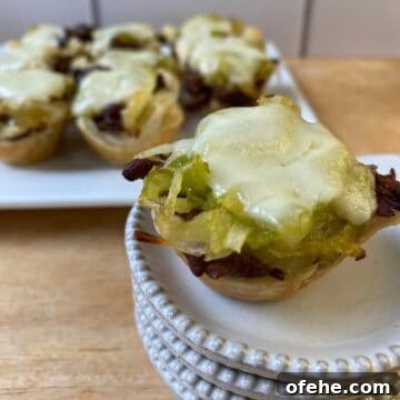 Philly Cheesesteak Bites Recipe: Savory Mini Sandwich Appetizers 15 Philly Cheesesteak bite on a small stack of dishes with the serving plate in the background.