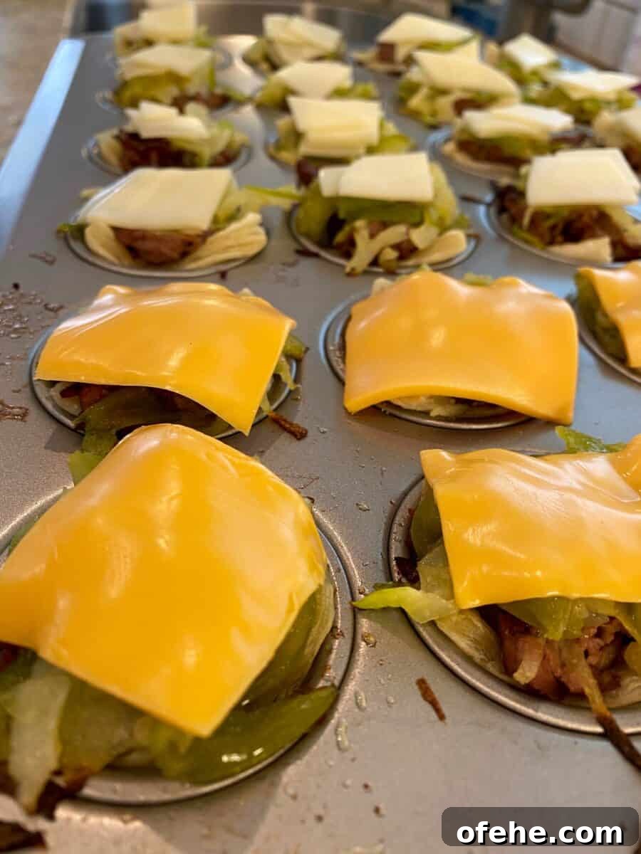 Philly Cheesesteak Bites Recipe: Savory Mini Sandwich Appetizers 4 Mini Philly Cheesesteaks in a mini-muffin pan with melted cheese on top of each one.