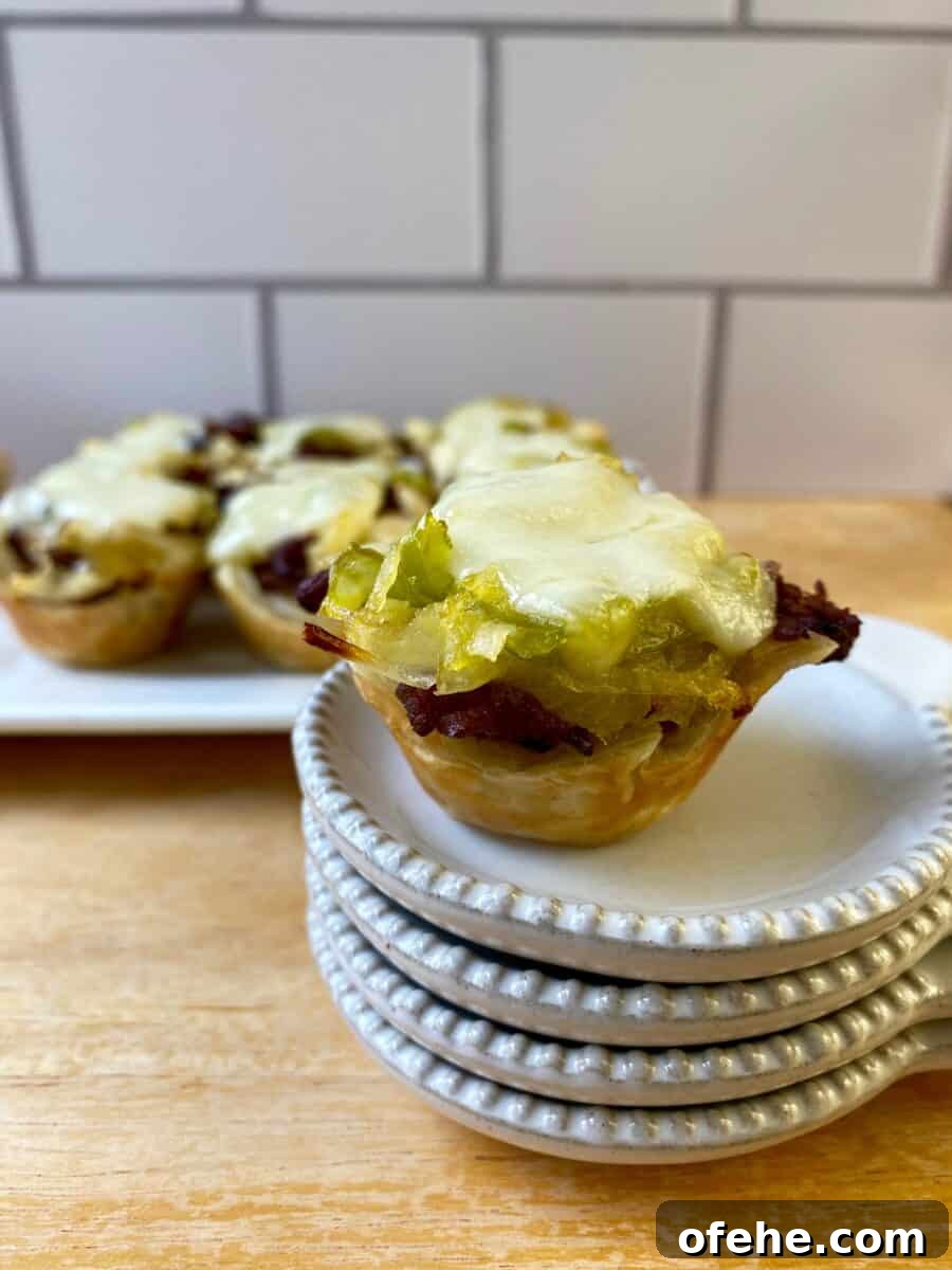 Philly Cheesesteak Bites Recipe: Savory Mini Sandwich Appetizers 5 Philly Cheesesteak Bite on a small stack of dishes with the serving plate in the background.