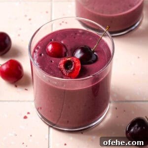 Creamy Cherry Smoothie Recipe for Fresh, Fruity Mornings 4 A cherry smoothie served in a small glass sitting on a tile counter.