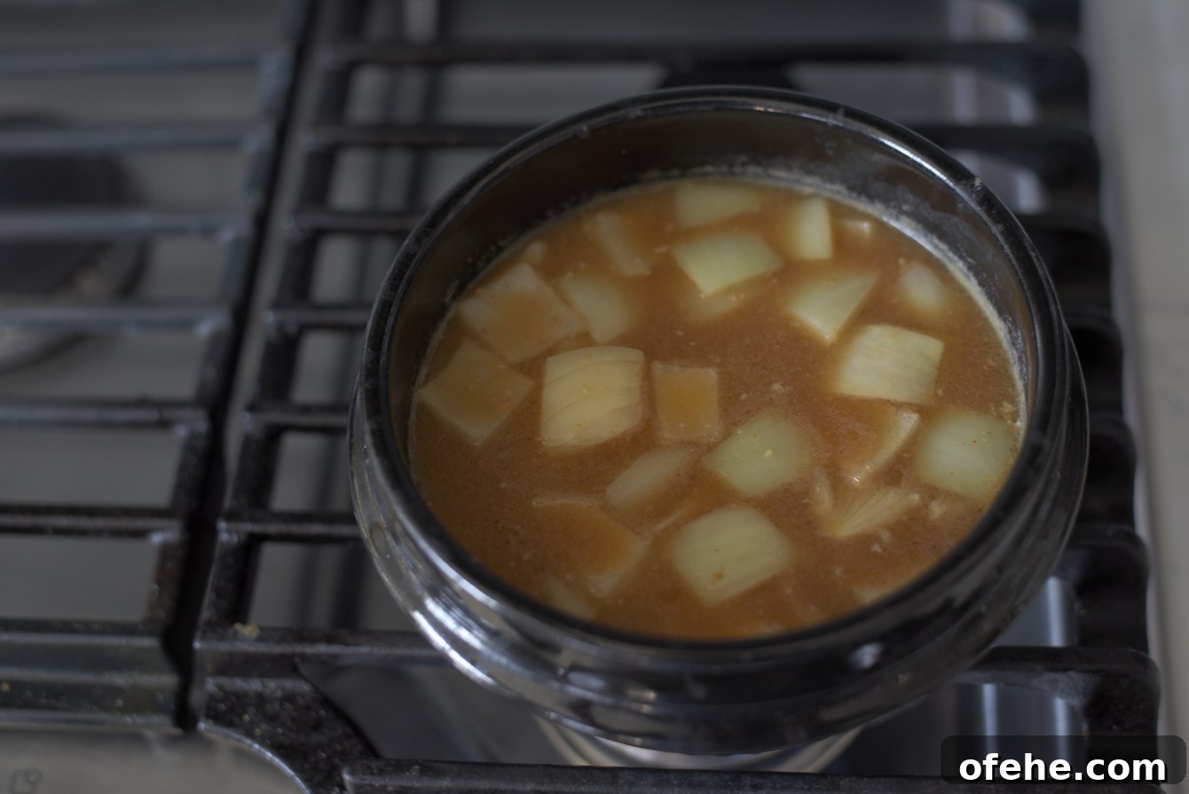 Authentic Doenjang Jjigae Recipe: Classic Korean Soybean Paste Stew 8 Diced onion added to simmering doenjang broth in a pot