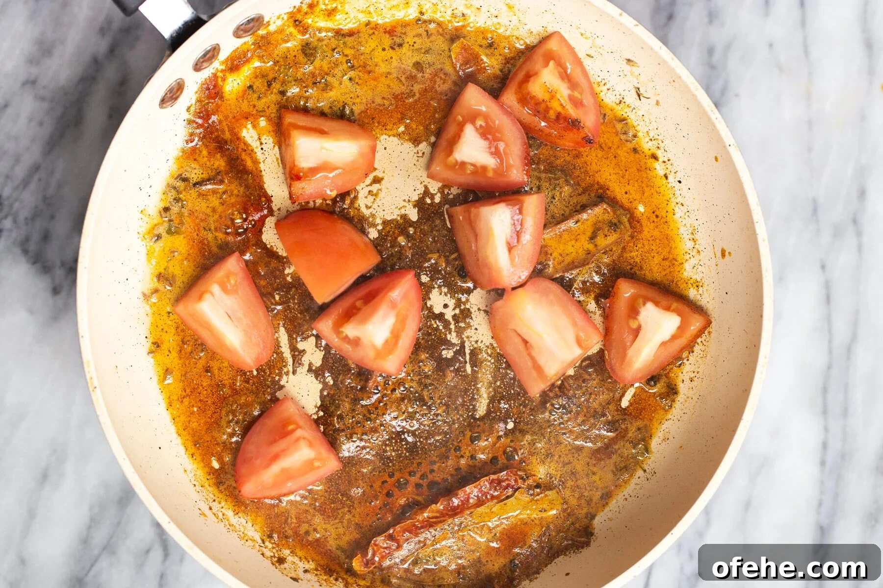 tomatoes being added to a pan with tempering 