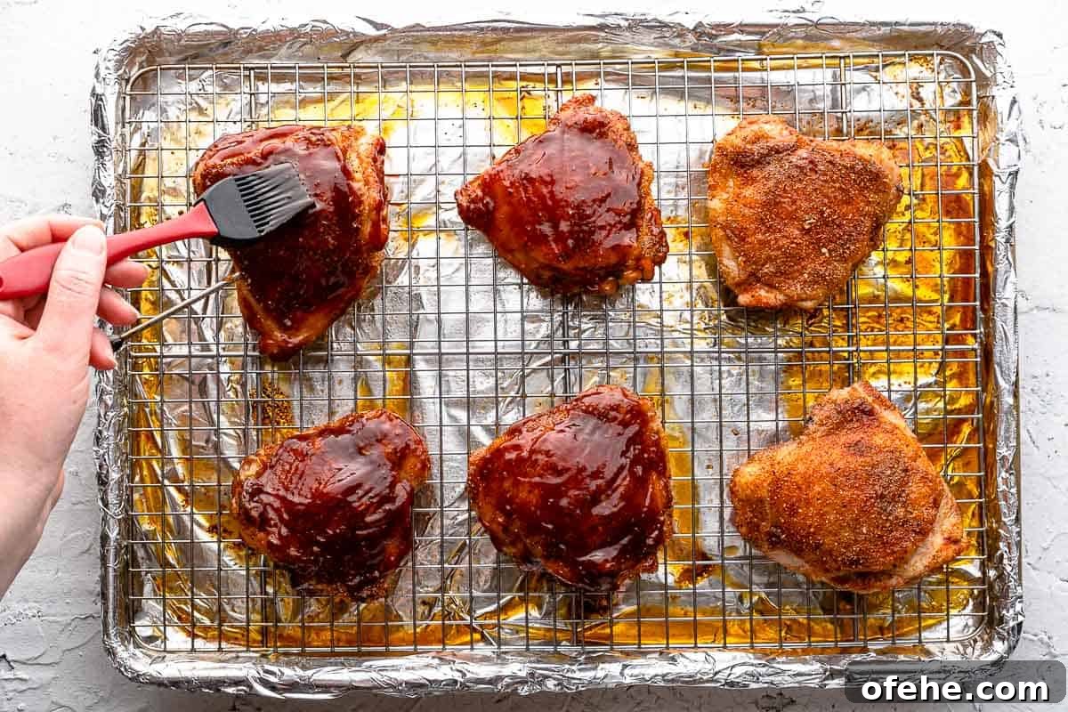 Juicy Baked BBQ Chicken Thighs with Crispy Skin 11 brush spreading bbq sauce on cooked chicken
