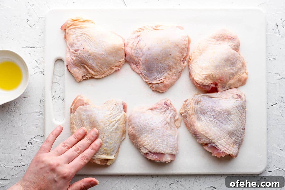 Juicy Baked BBQ Chicken Thighs with Crispy Skin 6 hand rubbing oil on chicken thighs