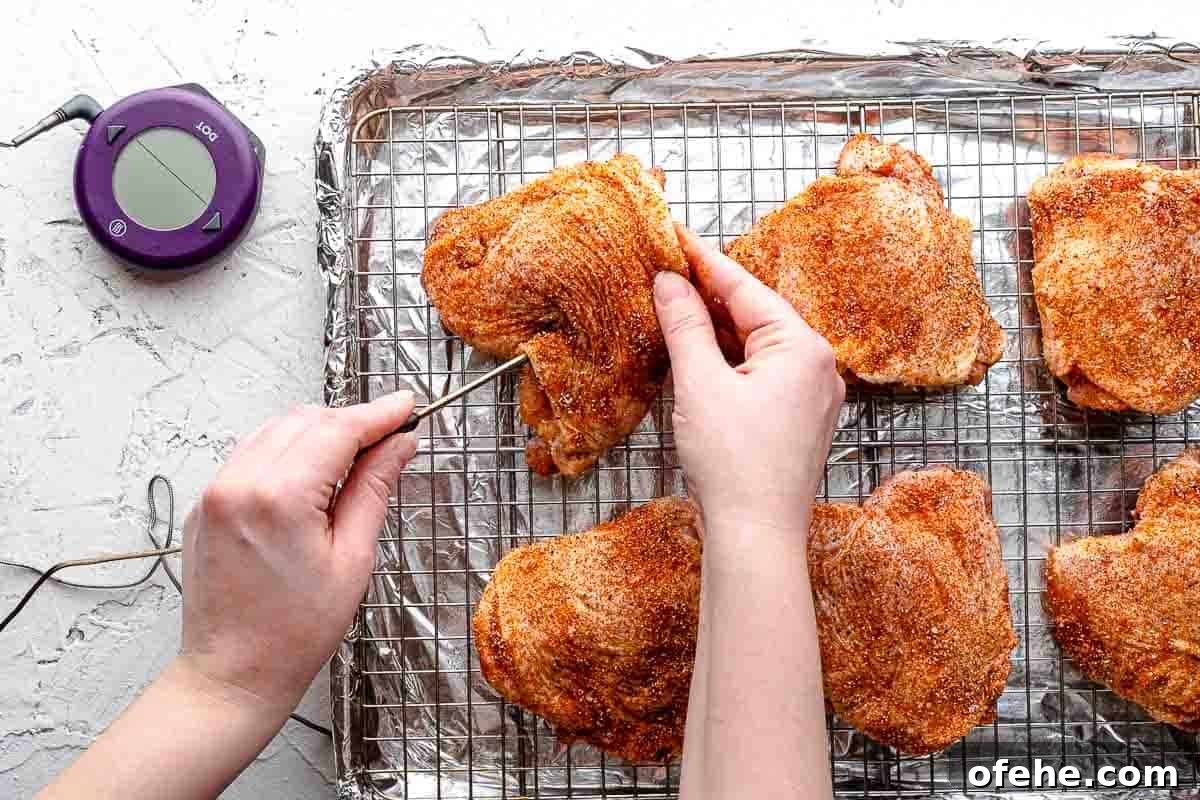 Juicy Baked BBQ Chicken Thighs with Crispy Skin 10 thermometer probe being inserted into chicken thigh