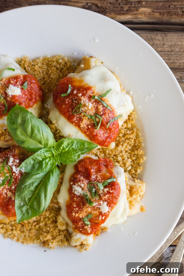 Crispy Chicken Parmesan with Toasted Panko Crust 12 Easy Chicken Parmesan With Toasted Panko on top of a thin layer of the toasted Panko on a serving plate, topped with red sauce, grated Parmesan and some thinly sliced fresh basil, with fresh basil leaves in the center of the serving plate.