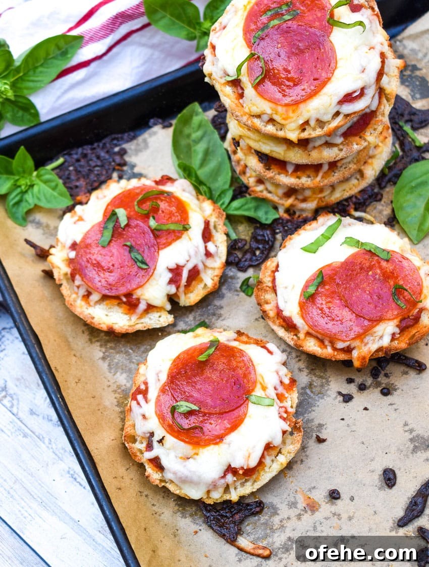 Mini English Muffin Pizzas: Quick Homemade Lunch or Snack 2 english muffin pizzas on a parchment paper lined baking sheet