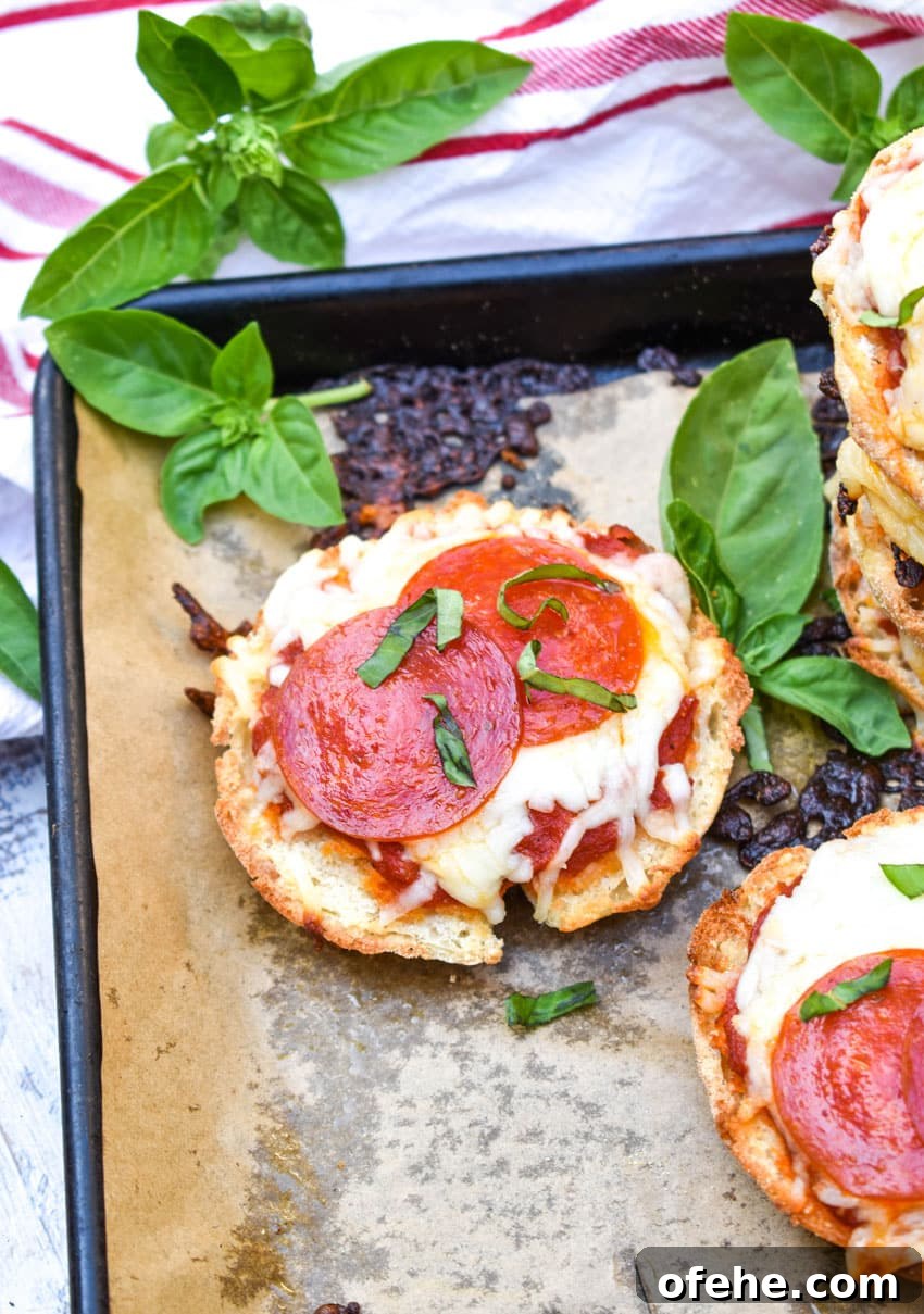 Mini English Muffin Pizzas: Quick Homemade Lunch or Snack 5 english muffin pizzas on a parchment paper lined baking sheet