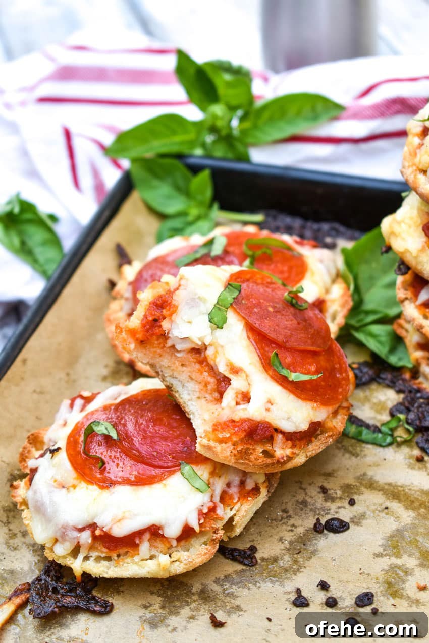 Mini English Muffin Pizzas: Quick Homemade Lunch or Snack 6 english muffin pizzas on a parchment paper lined baking sheet