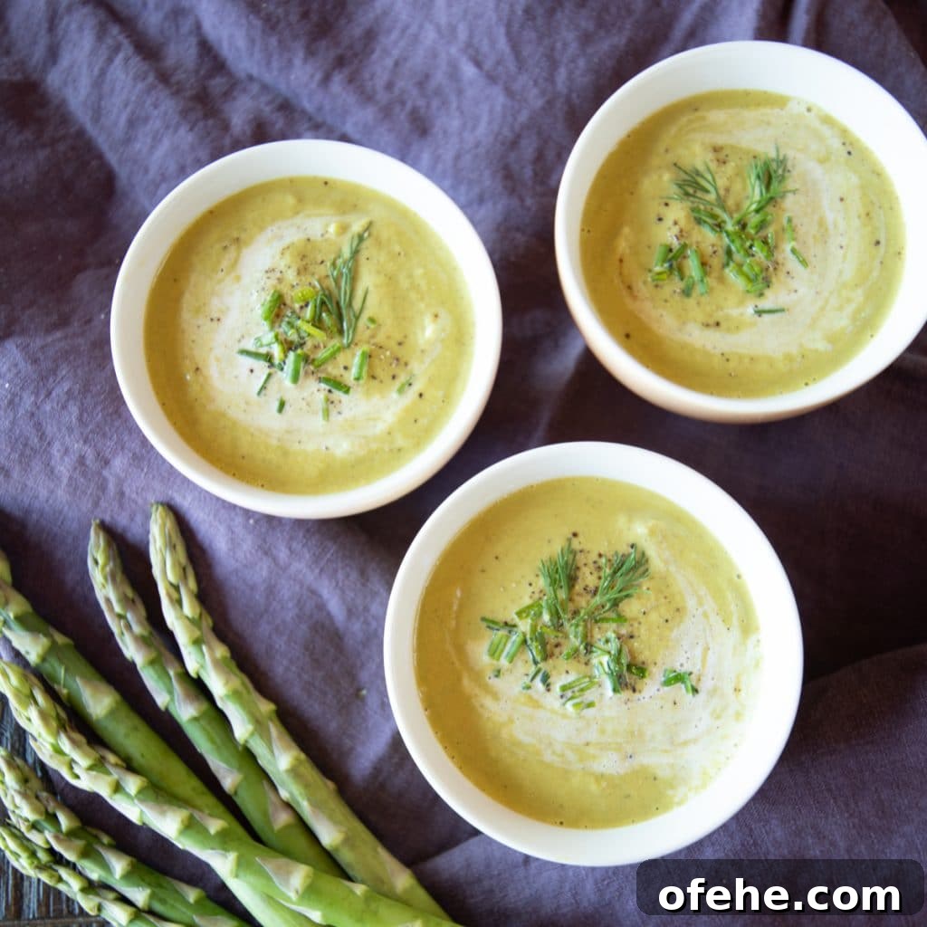 Bowls of cream of asparagus soup garnished with herbs.