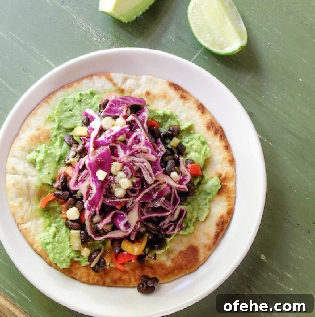 Tostada topped with guacamole, black beans, and a cabbage salad.