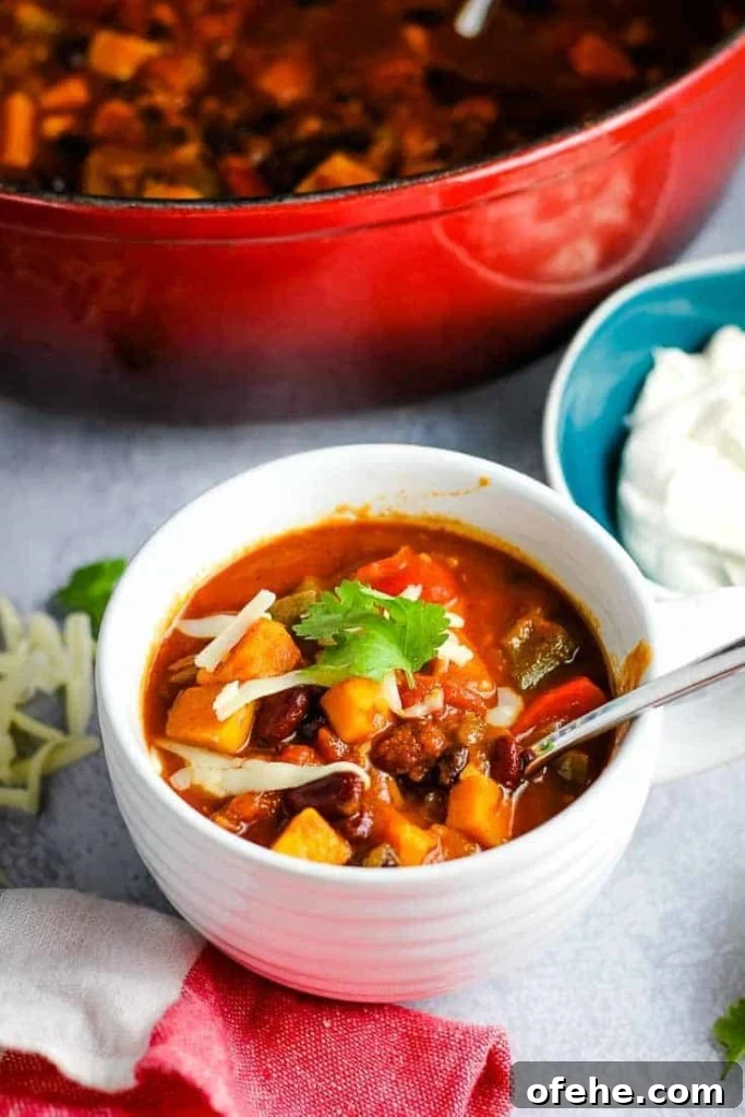 A bowl of vegetarian sweet potato chili topped with cheddar and cilantro