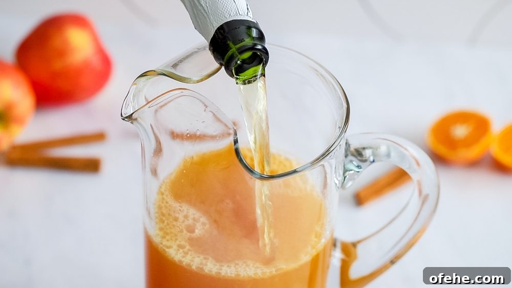 Sparkling Apple Cider Rum Punch Recipe for Fall Gatherings 11 rum punch in a glass with an apple cinnamon stick and slice of orange