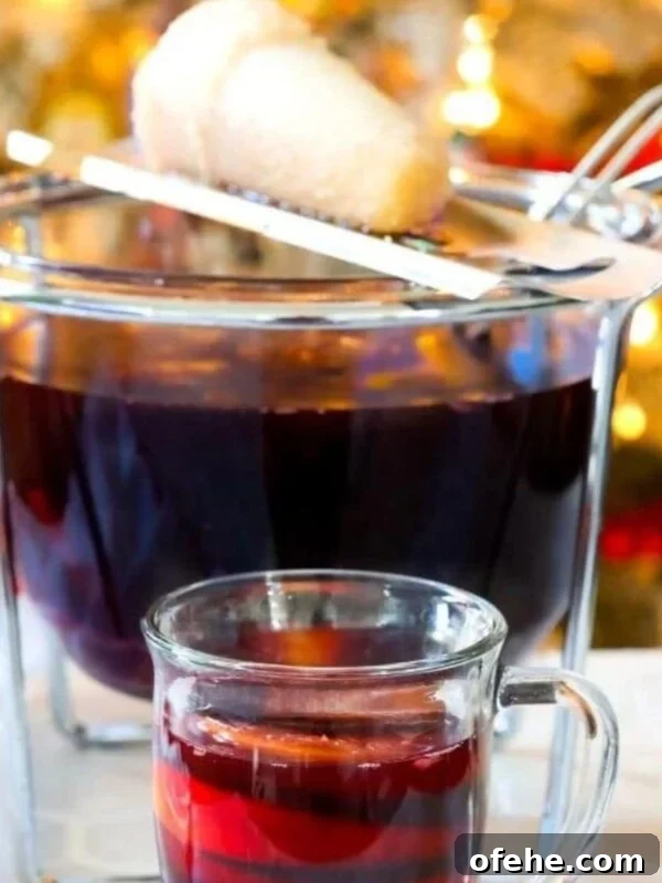 Sparkling Apple Cider Rum Punch Recipe for Fall Gatherings 7 Feuerzangenbowle in a mug in front of a punch bowl