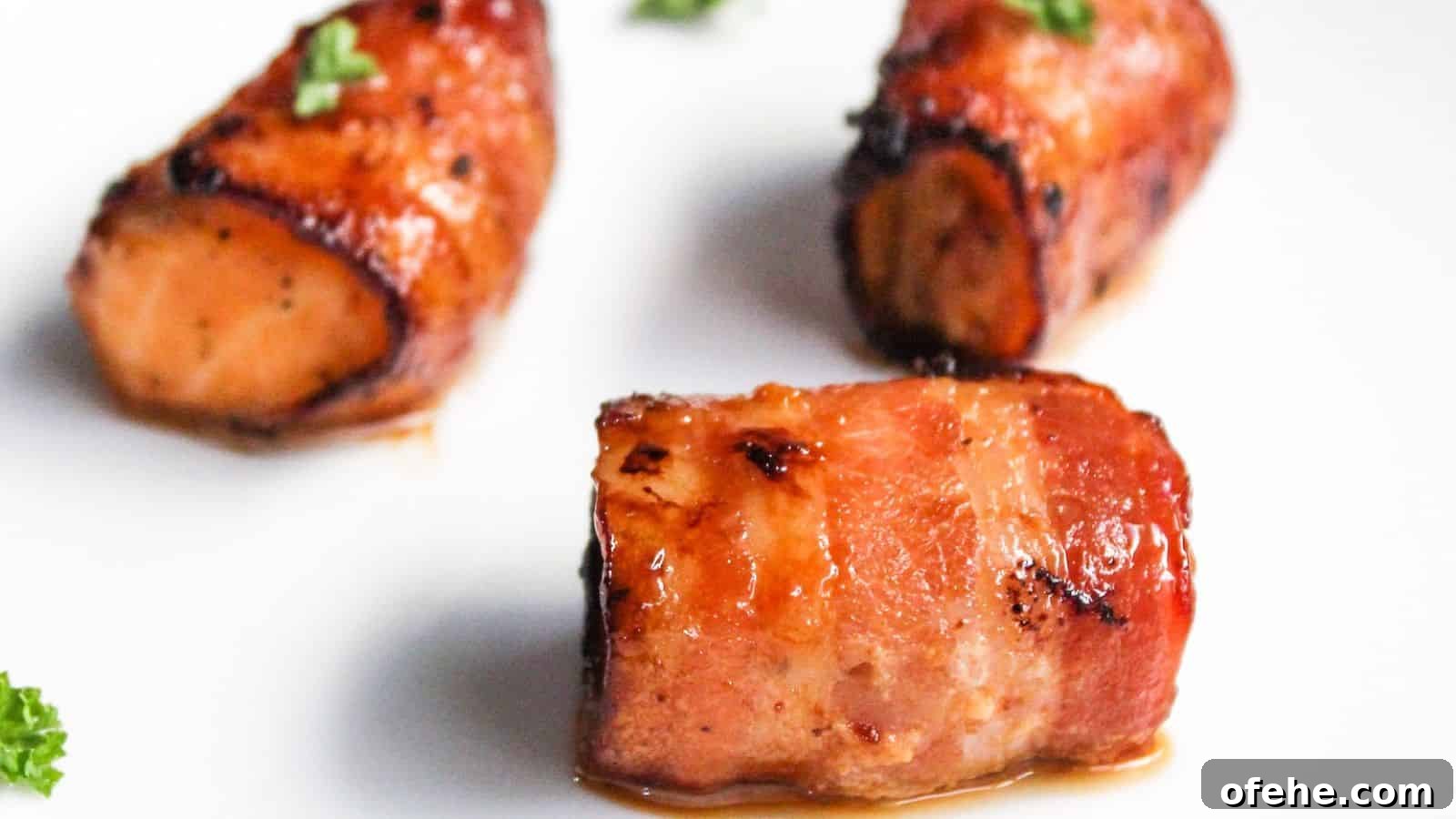 30 Quick Appetizers to Impress Guests Without Fuss 13 Three pieces of bacon-wrapped salmon bites garnished with parsley on a white plate.