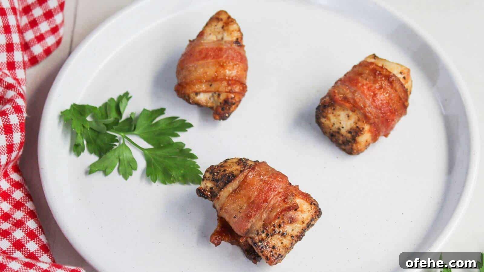 30 Quick Appetizers to Impress Guests Without Fuss 21 Three bacon-wrapped pieces of chicken on a white plate with a sprig of parsley and a red and white checkered cloth on the side.