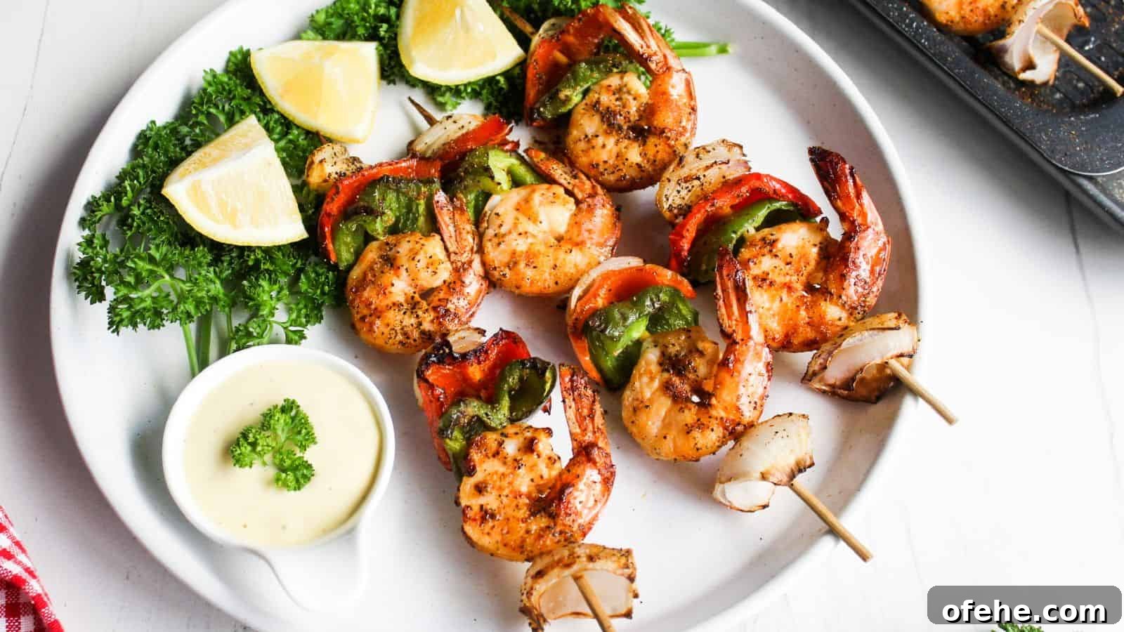 30 Quick Appetizers to Impress Guests Without Fuss 27 Grilled shrimp skewers with red and green bell peppers, served with lemon wedges and a dipping sauce on a white plate.