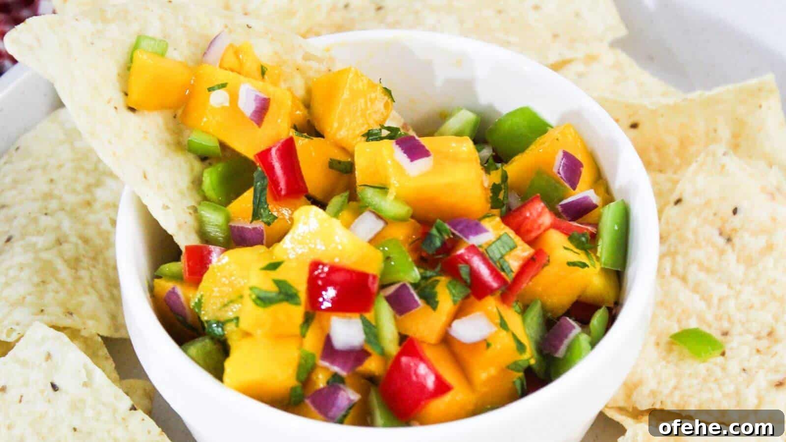 30 Quick Appetizers to Impress Guests Without Fuss 31 A white bowl filled with diced mango, red onion, red bell pepper, and green bell pepper salsa is surrounded by tortilla chips.