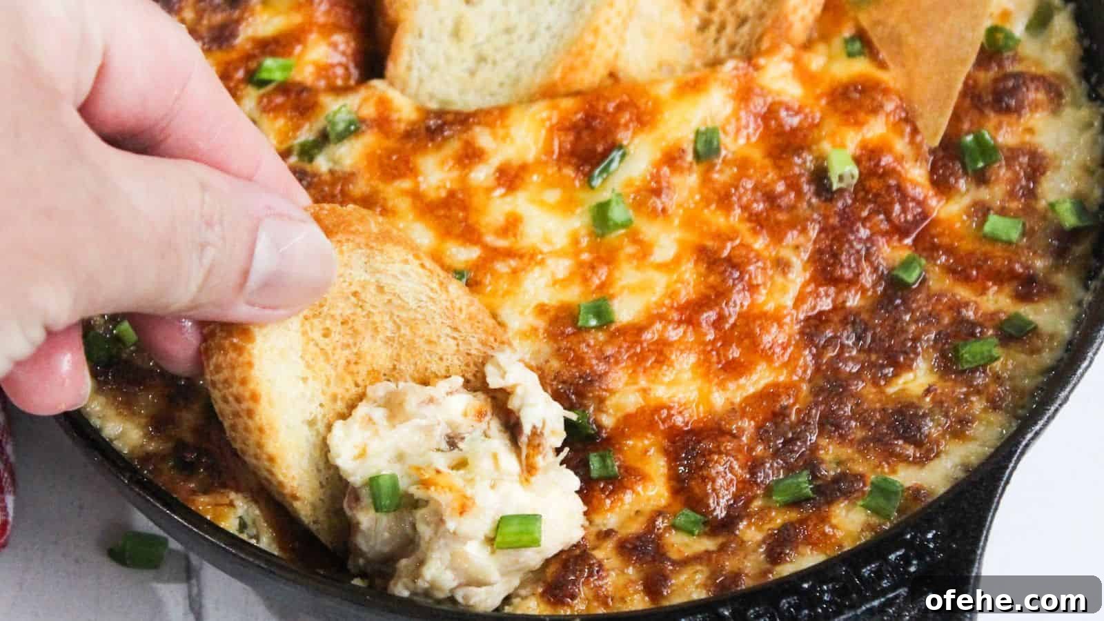 30 Quick Appetizers to Impress Guests Without Fuss 10 A person dipping a piece of bread into a skillet of cheesy dip.