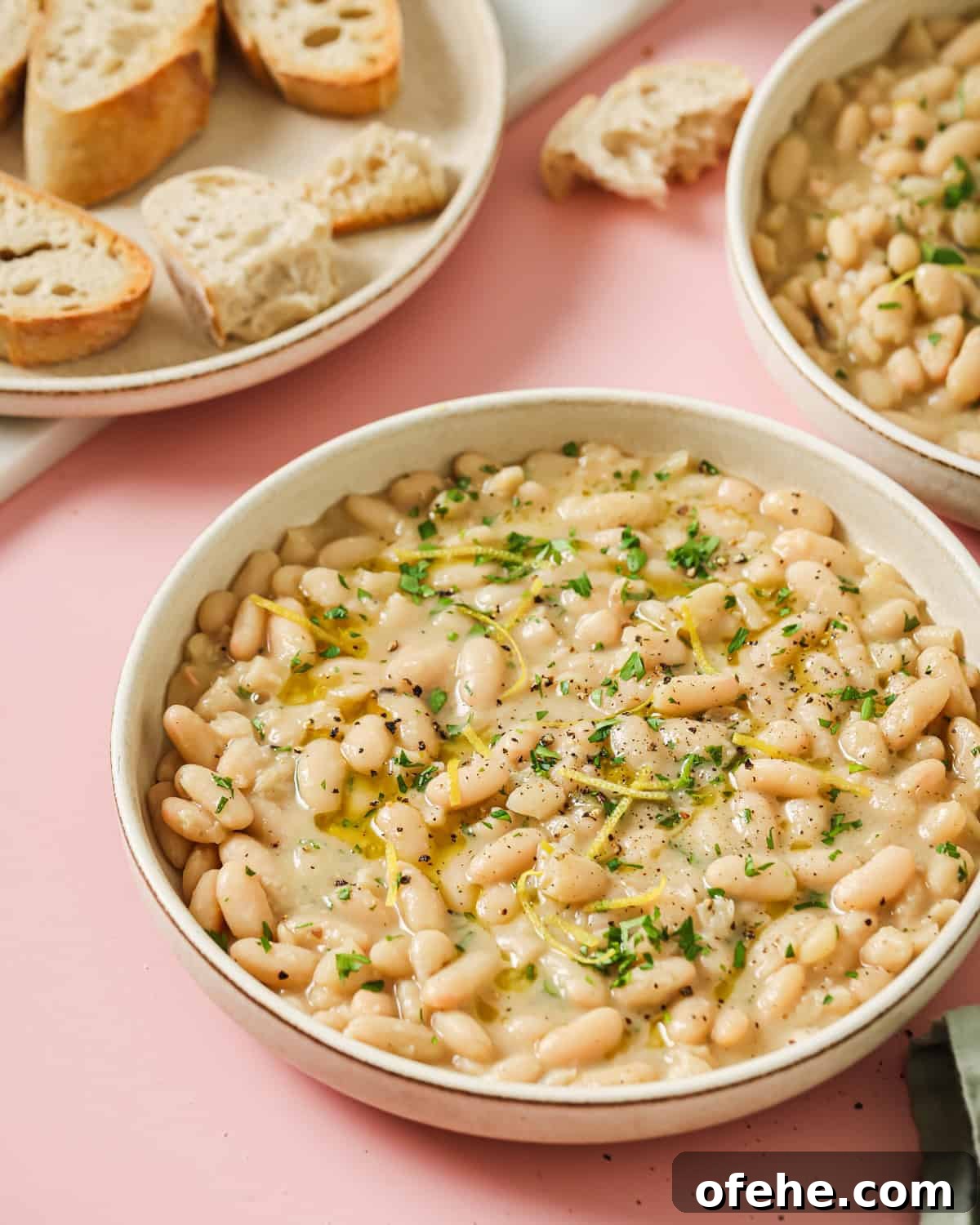 How to Perfectly Cook Dried Beans: Step-by-Step Guide 6 a bowl of creamy white beans on a pink surface with bread in background.