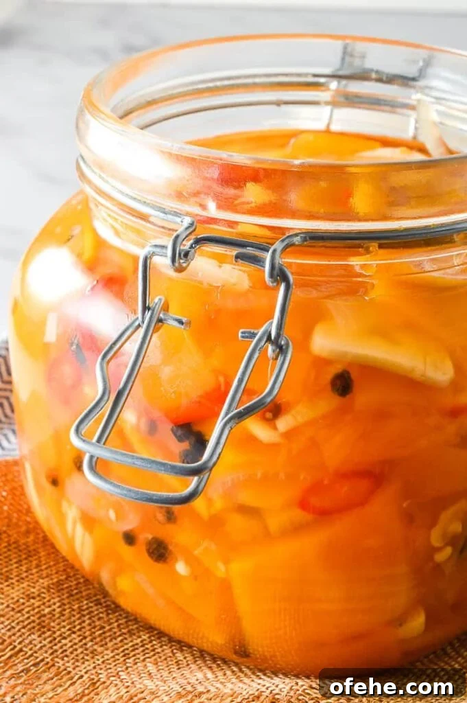 Side view of preserves jar filled with orange vegetables and garlic
