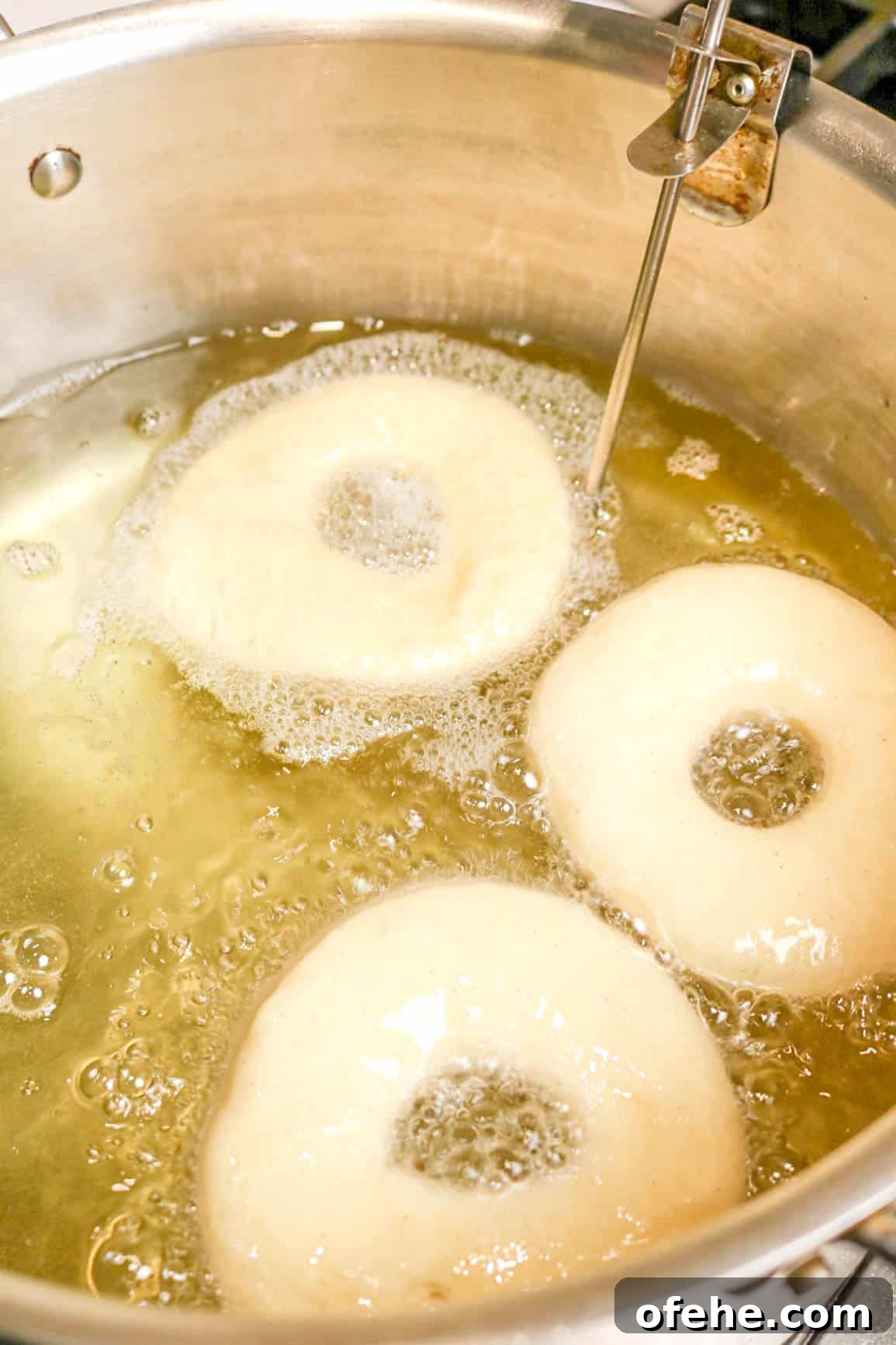 three doughnuts frying in hot oil