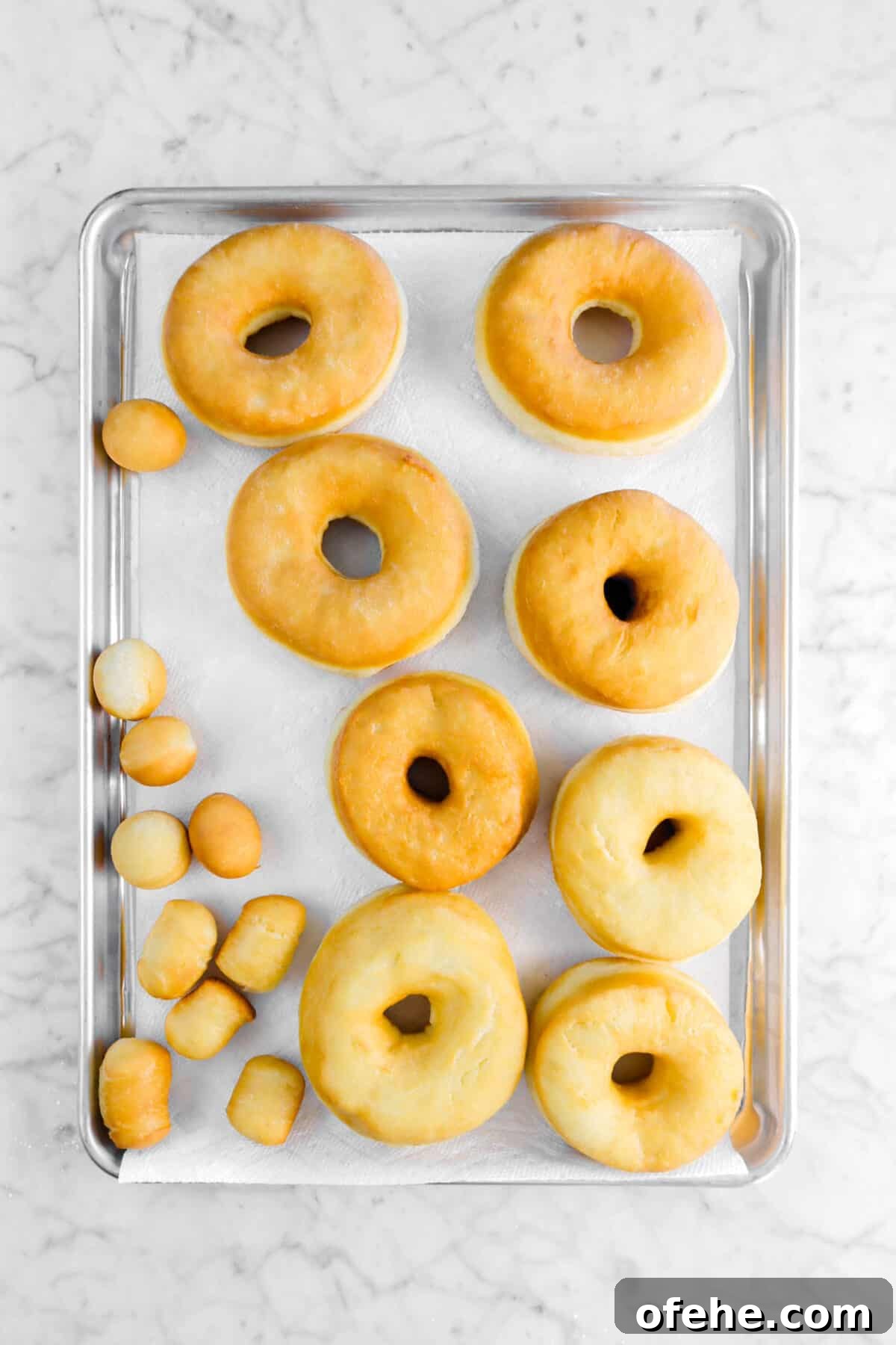 fried doughnuts on sheet pan with paper towels