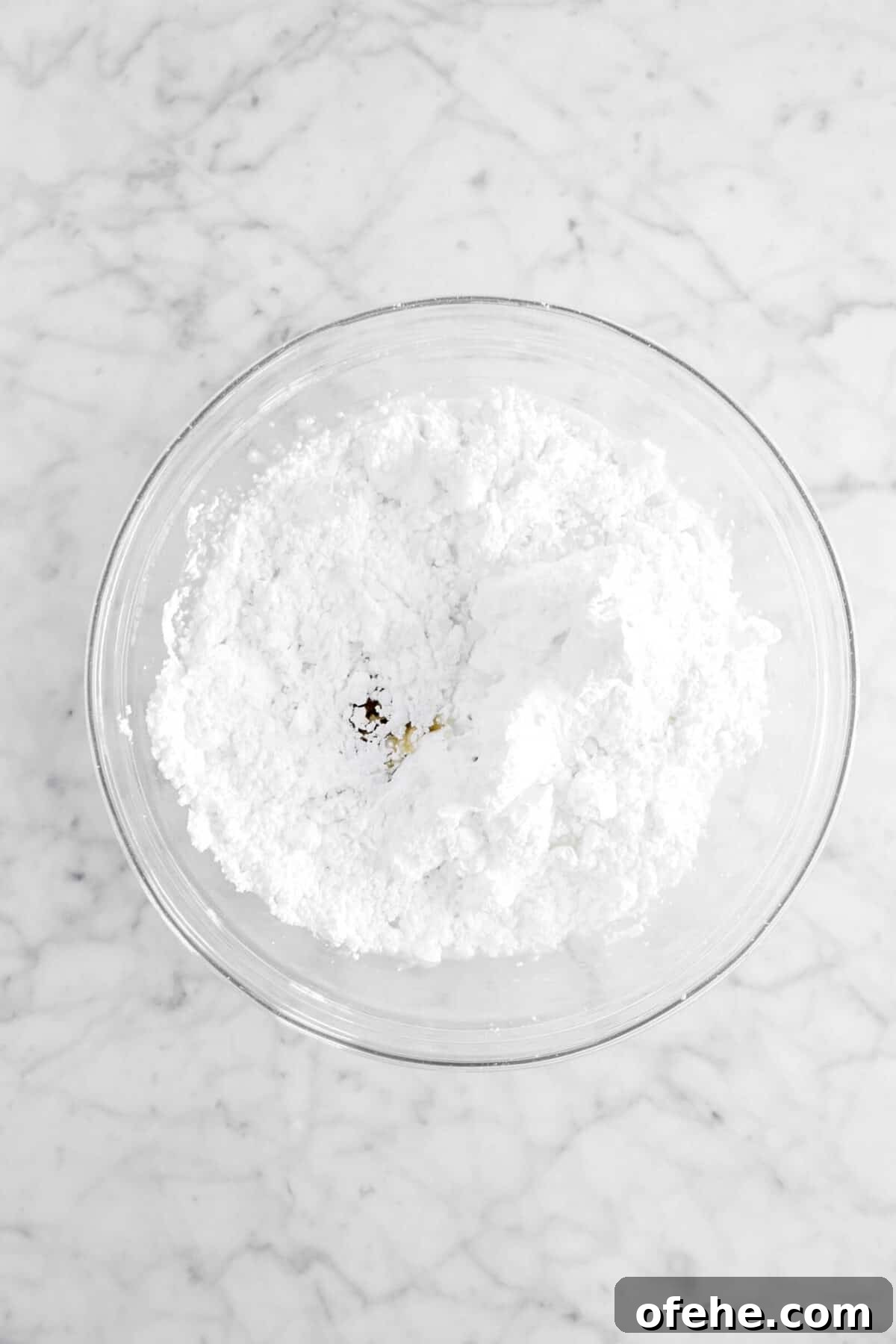 powdered sugar, vanilla, and milk in glass bowl
