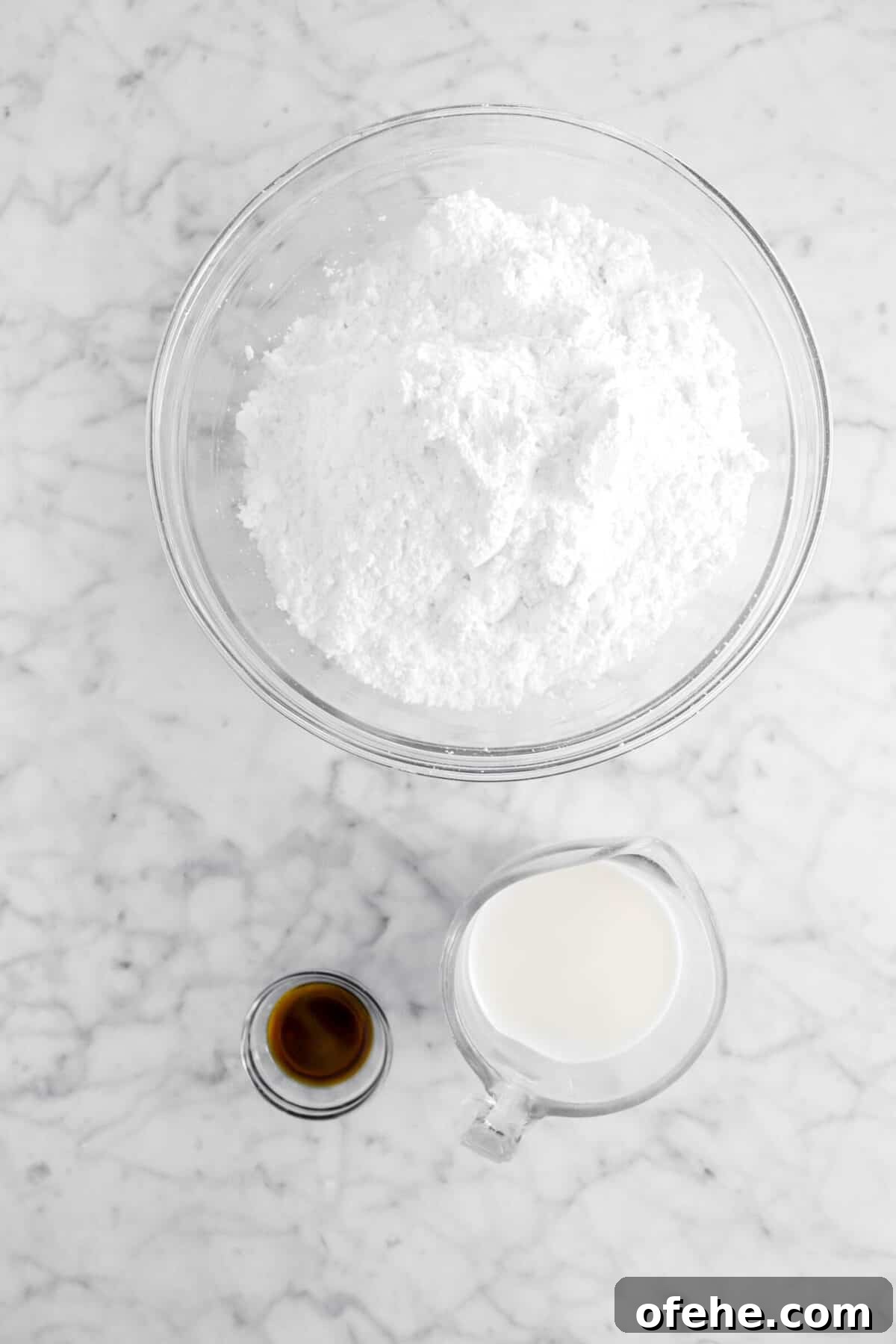 powdered sugar, milk, and vanilla on marble counter