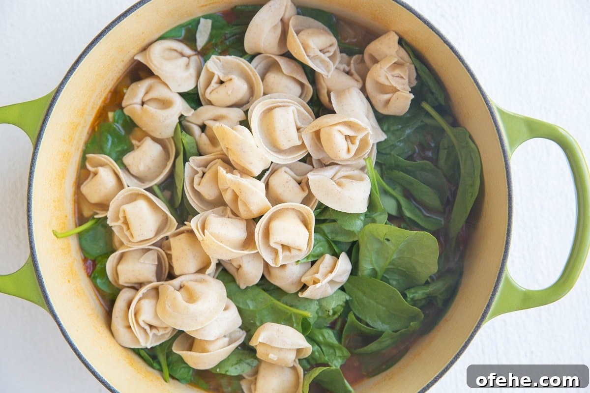 Pot of soup with spinach and tortellini on top