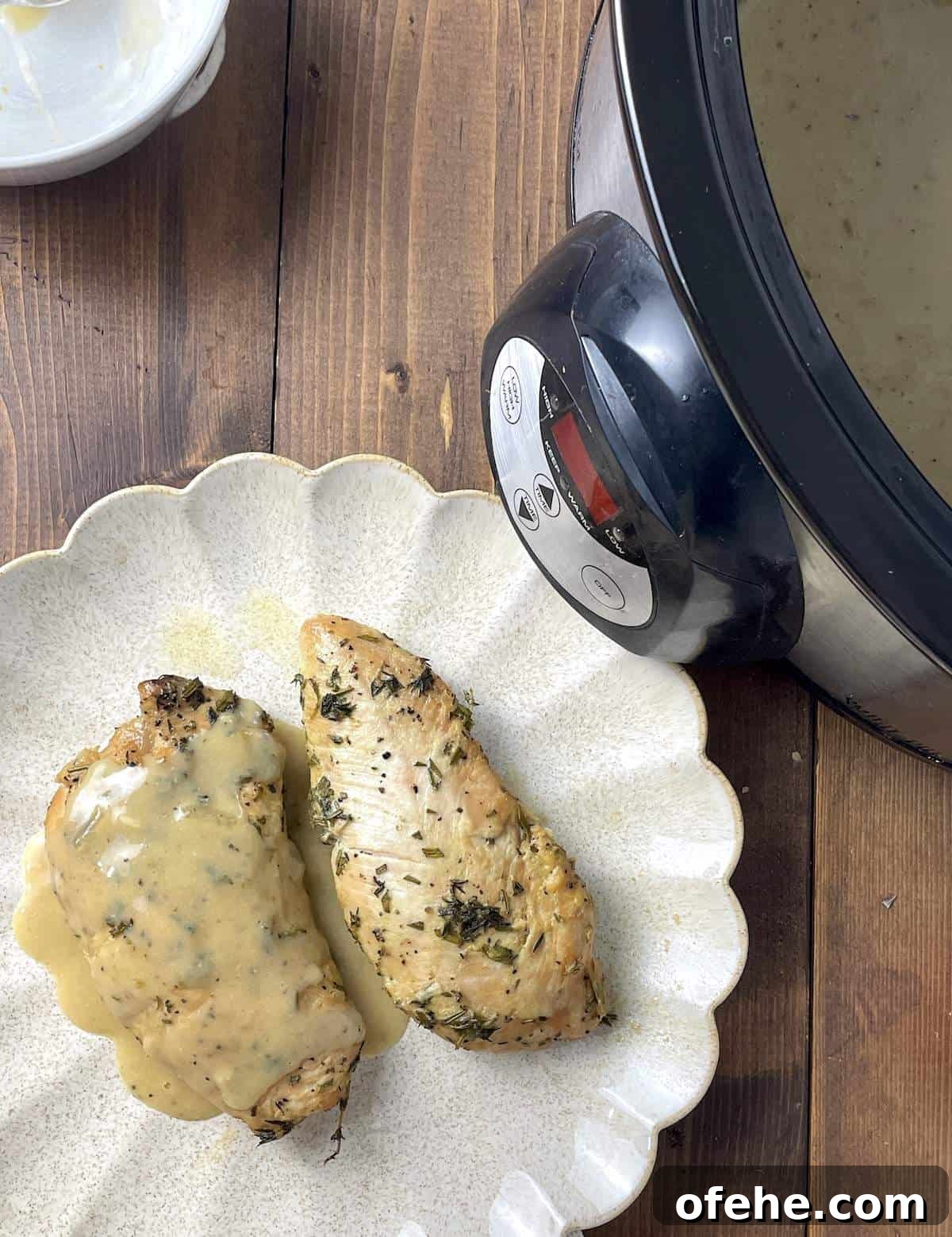 Crockpot Turkey Tenderloins in Honey Mustard Gravy 8 Two cooked turkey tenderloins with gravy on a scalloped plate next to a crockpot.