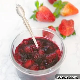 Fruit Compote Ideas: Delicious Pancake Toppers and More 11 fruit compote in a glass bowl with silver spoon and fresh strawberries on the side