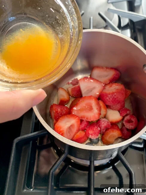 Fruit Compote Ideas: Delicious Pancake Toppers and More 6 Hand adding citrus to berries in saucepan.