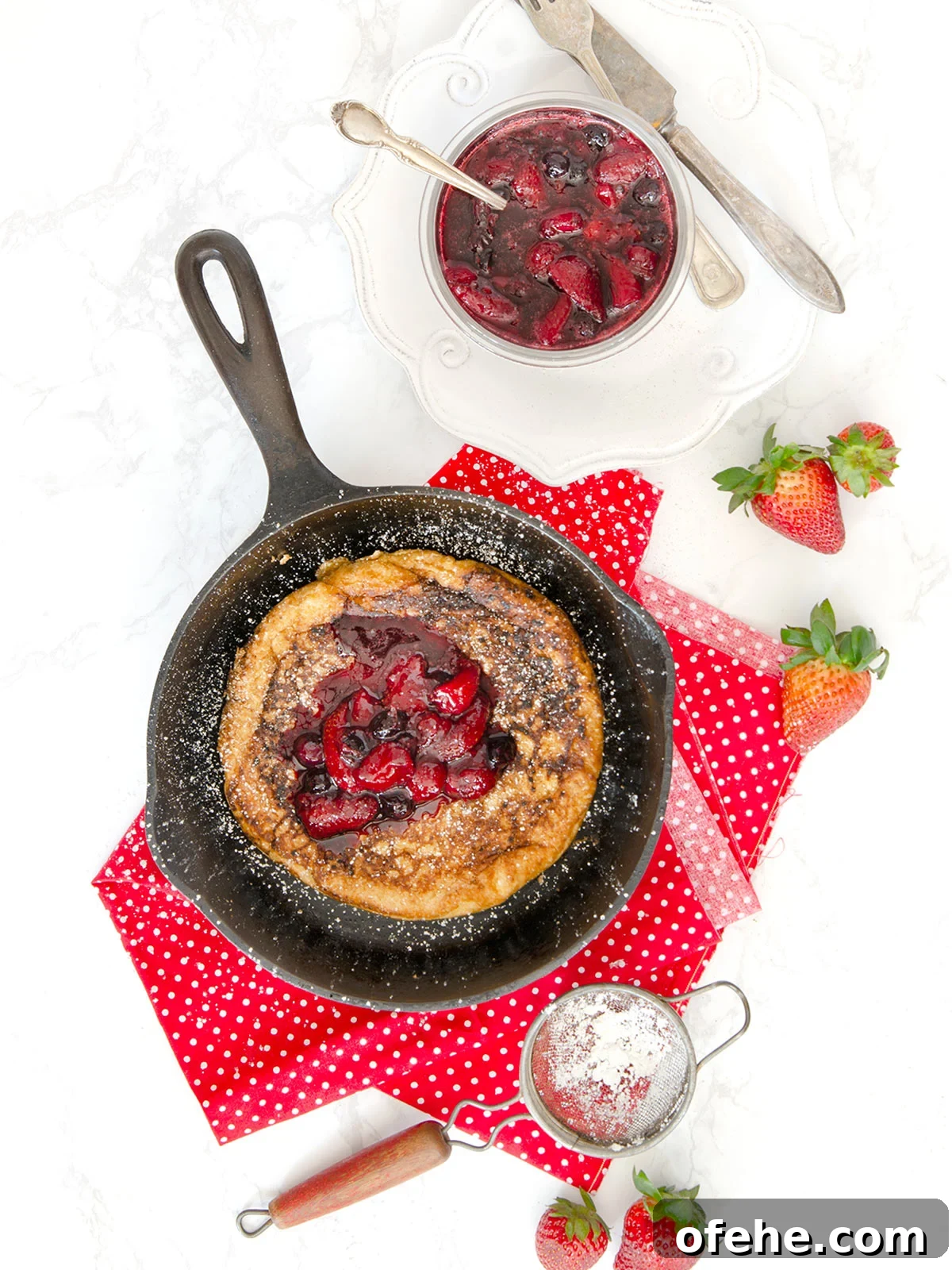 Fruit Compote Ideas: Delicious Pancake Toppers and More 9 Matzo meal pancake in a cast iron pan with fruit compote on top and on the side in a clear glass bowl.